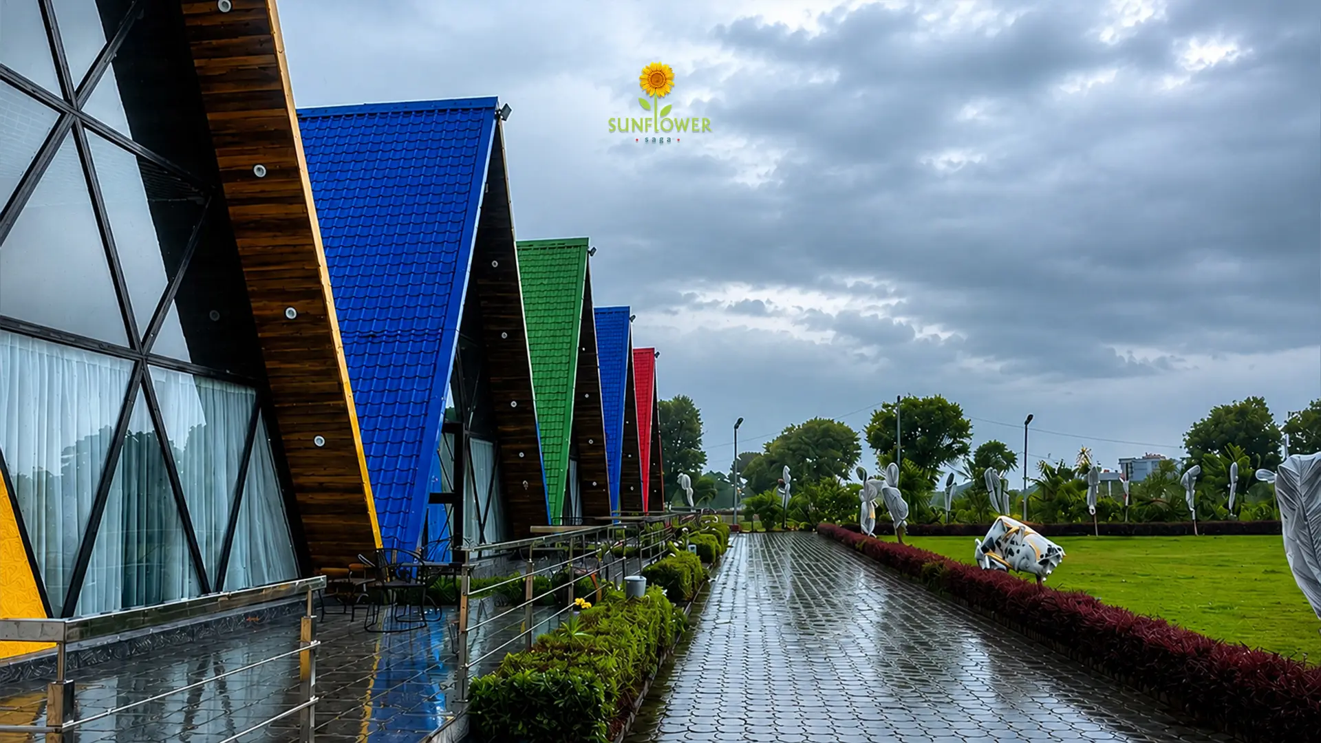 Colorful A-frame cottages at Sunflower Saga surrounded by lush monsoon landscape and cloudy skies